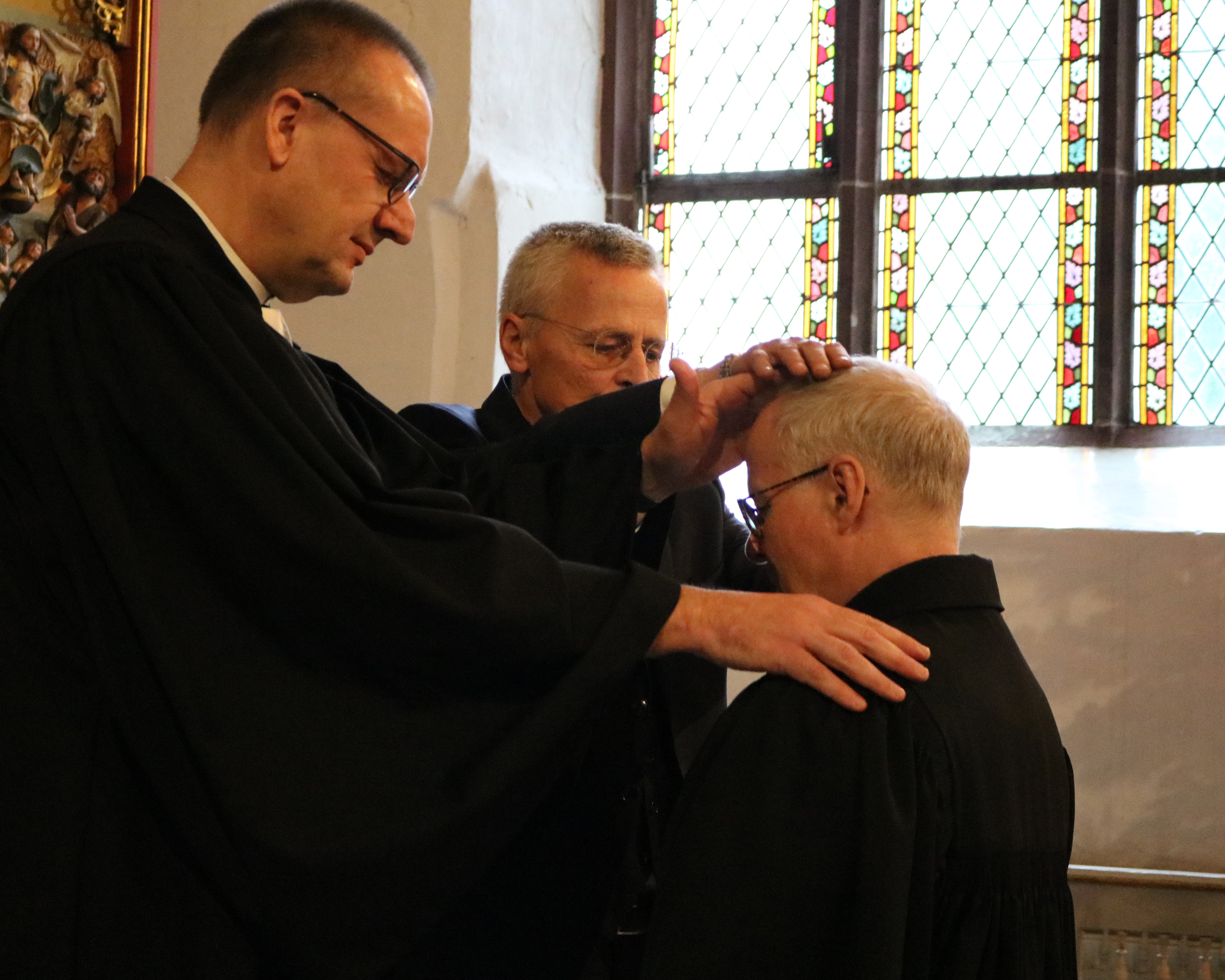 Bischof Adomeit und Uwe K. Kollmann segnen Pfarrer Thomas Feldim Entpflichtungsgottesdienst. Foto: Kerstin Kempermann