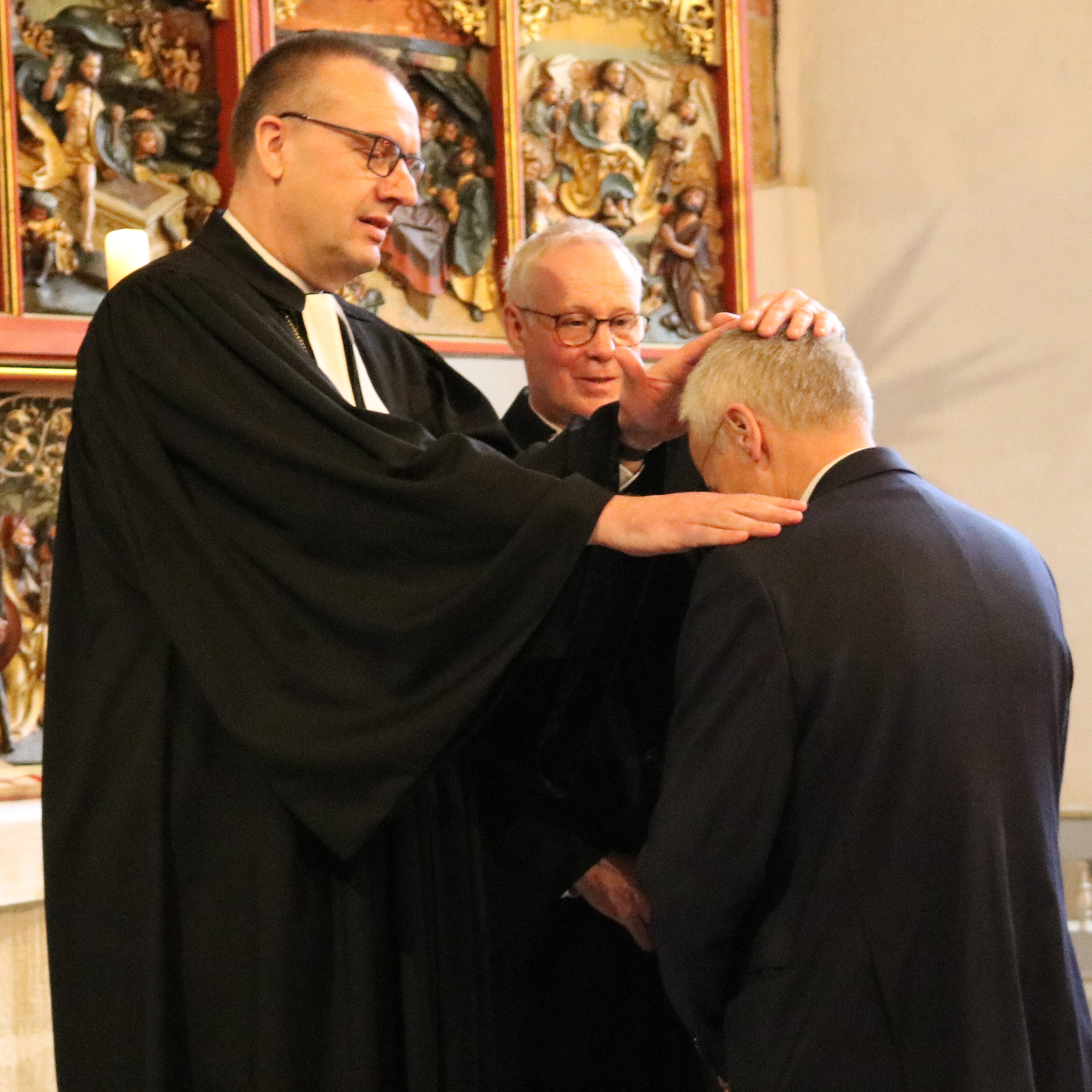 Bischof Adomeit und Pfarrer Thomas Feld segnen Uwe K. Kollmann im Entpflichtungsgottesdienst. Foto: Kerstin Kempermann